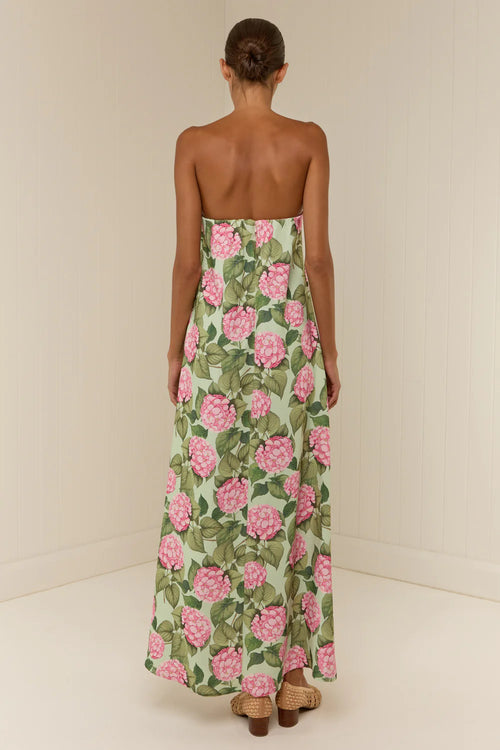 Woman wearing a strapless floral dress with pink flowers on a plain background