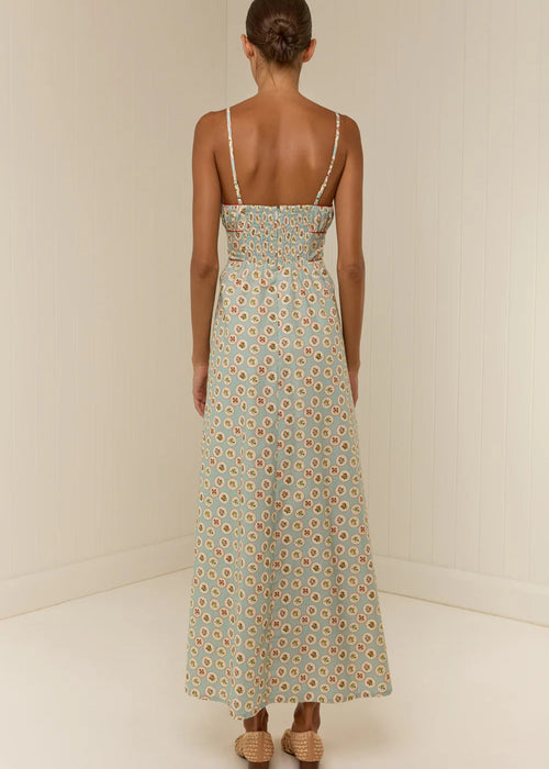 Woman wearing a floral dress with thin straps on a plain background