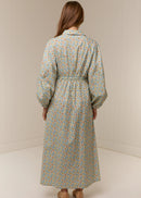 Woman wearing a long floral dress against a plain background