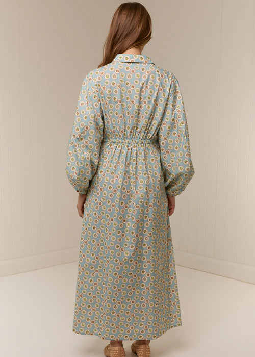 Woman wearing a long floral dress against a plain background