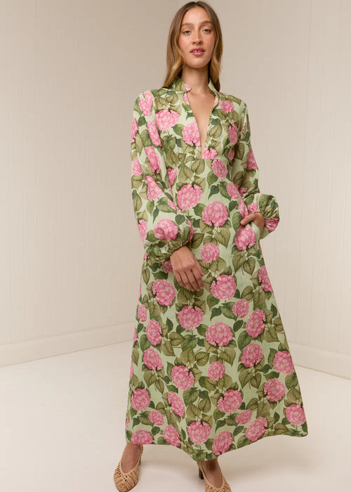 Woman wearing a floral dress with pink flowers on a plain background
