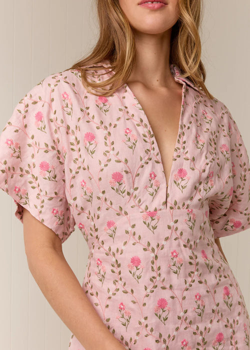 Woman wearing a pink floral dress against a neutral background