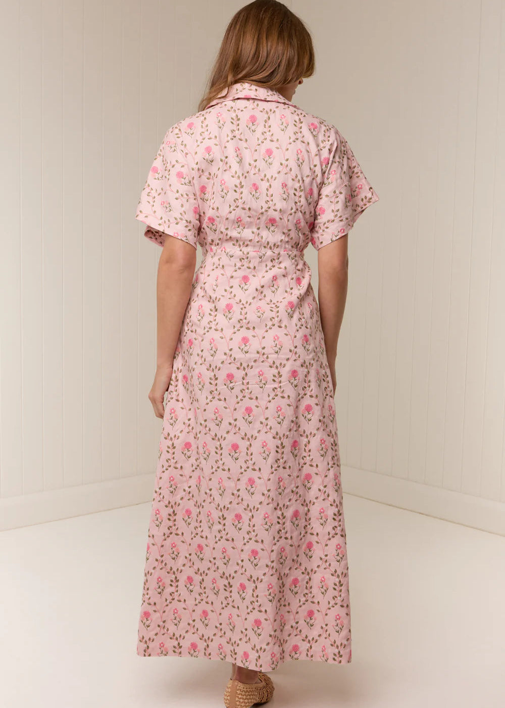 Woman wearing a pink floral dress against a white background