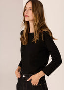 Woman wearing a black long-sleeve top  against a plain background
