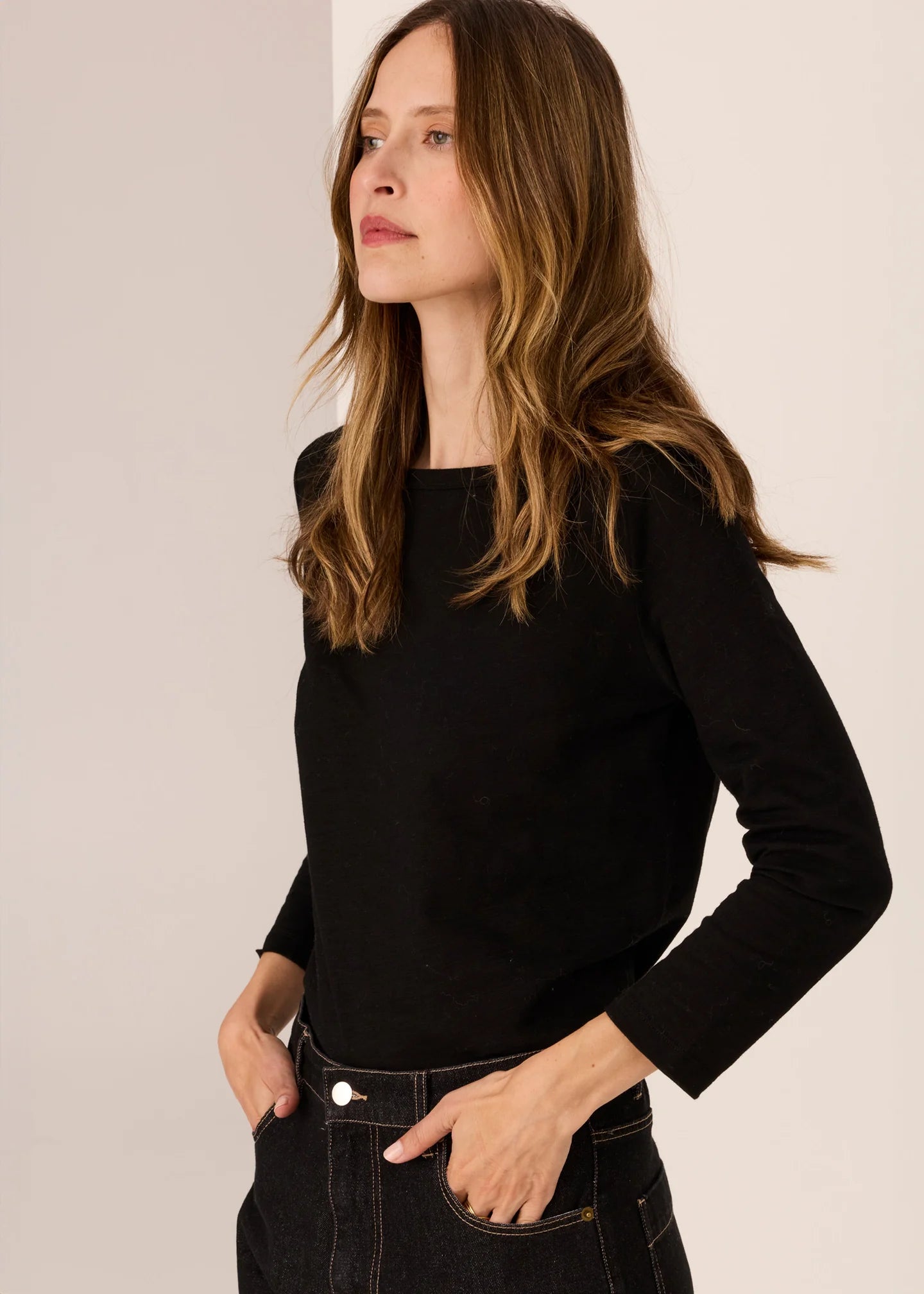 Woman wearing a black long-sleeve top  against a plain background