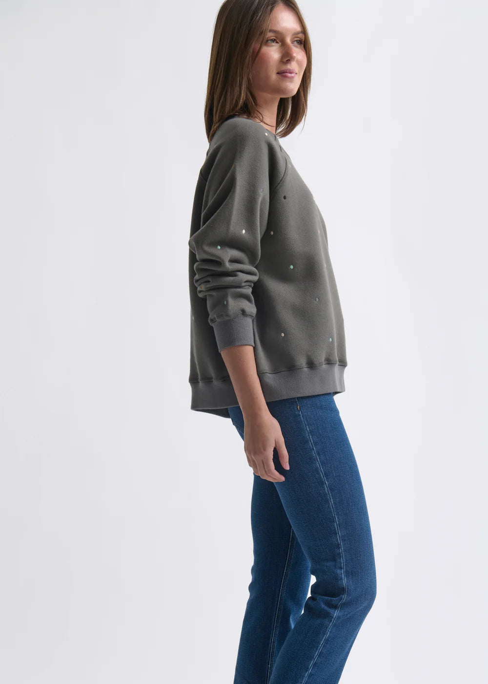 Woman wearing a grey sweatshirt with dot patterns  on a white background