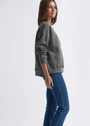 Woman wearing a grey sweatshirt with dot patterns  on a white background