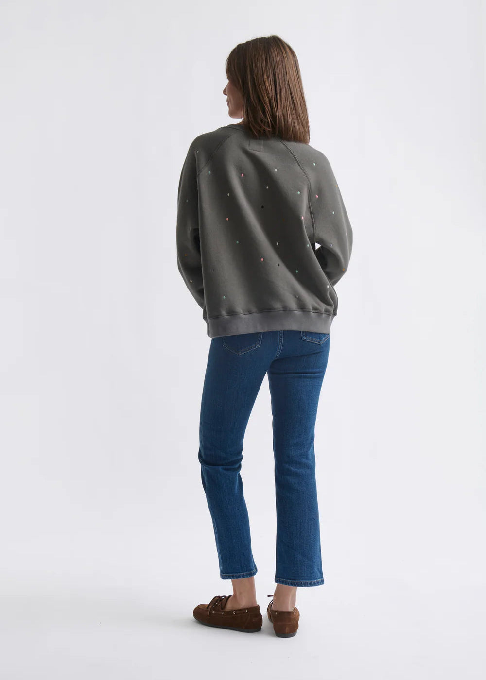 Woman wearing a grey sweatshirt with dot patterns  on a white background