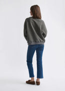 Woman wearing a grey sweatshirt with dot patterns  on a white background