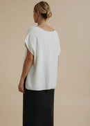 Woman modelling a white top on a beige background