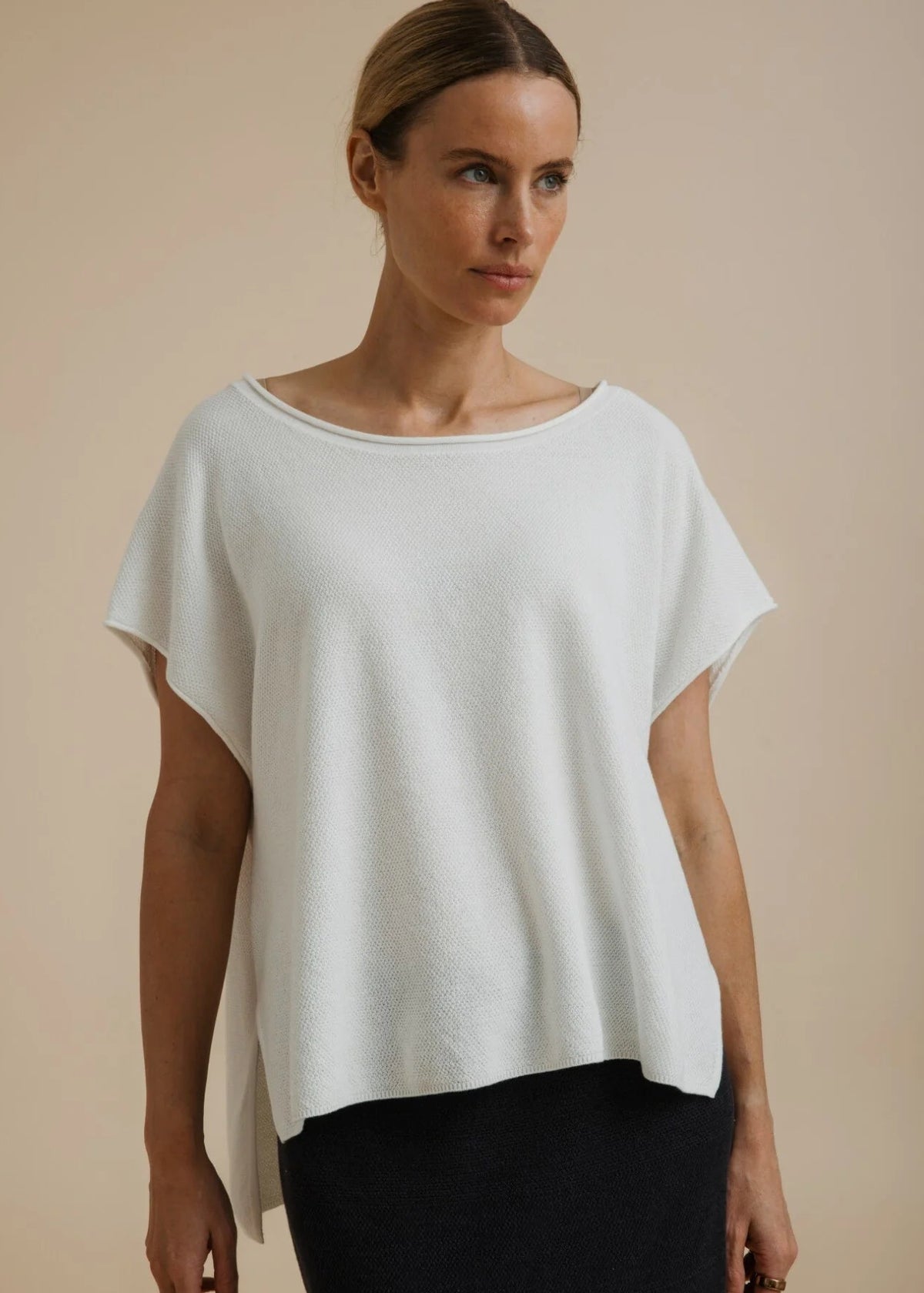 Woman modelling a white top on a beige background