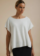 Woman modelling a white top on a beige background