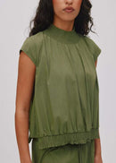 Woman wearing a green sleeveless top and pants on a white background