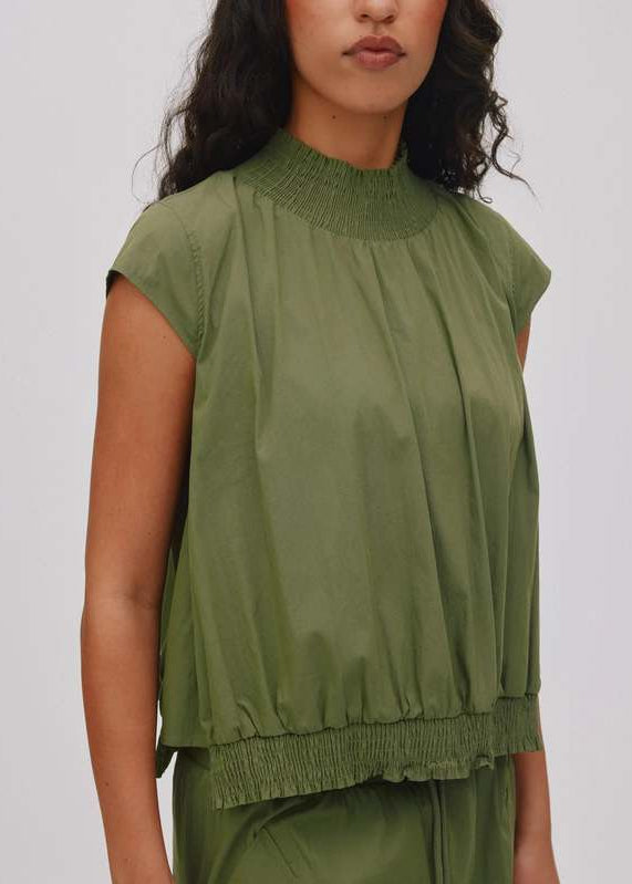 Woman wearing a green sleeveless top and pants on a white background
