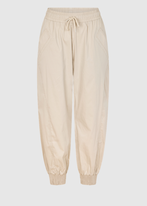 A pair of light beige jogger pants with an elastic waistband, drawstring, and elastic cuffs, shown against a solid light gray background.