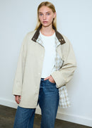 Person wearing a beige coat  against a light background