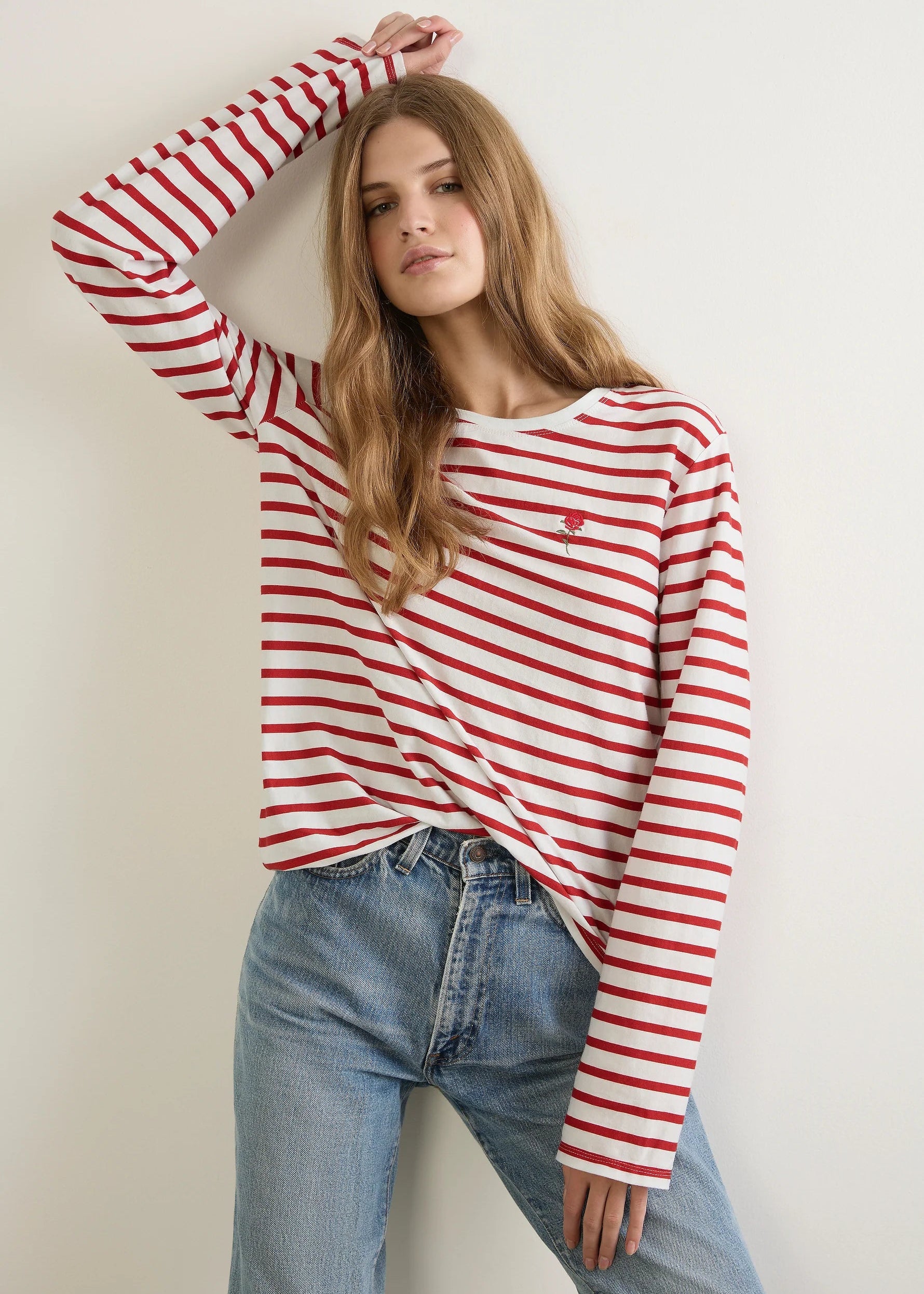 Person wearing a red and white striped long-sleeve shirt and blue jeans against a plain background