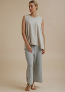 Woman wearing a light beige sleeveless top and pants on a beige background