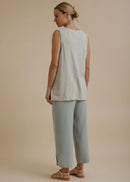 Woman wearing a light beige sleeveless top and pants on a beige background