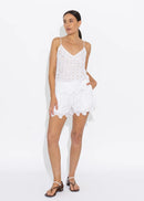 Woman wearing a white lace cami on a plain background