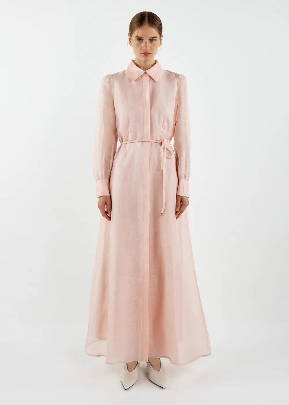 Woman wearing a long light pink dress on a white background
