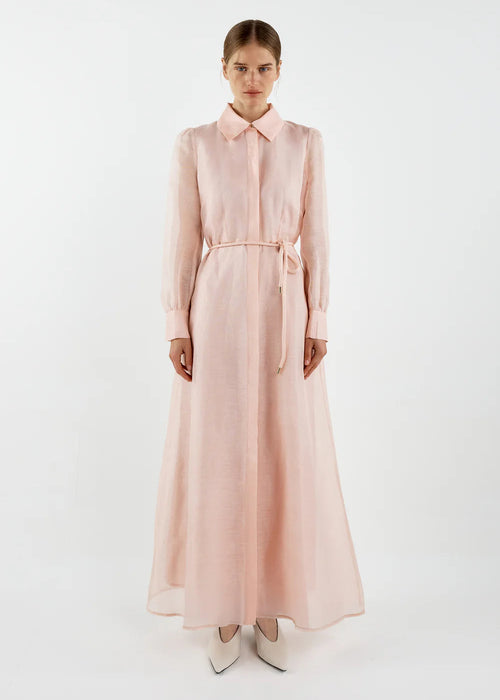 Woman wearing a long light pink dress on a white background