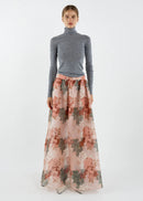 Woman wearing a grey turtleneck and floral skirt on a white background