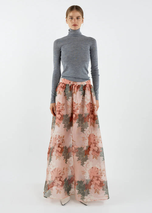 Woman wearing a grey turtleneck and floral skirt on a white background