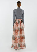 Person wearing a floral skirt and grey top on a white background