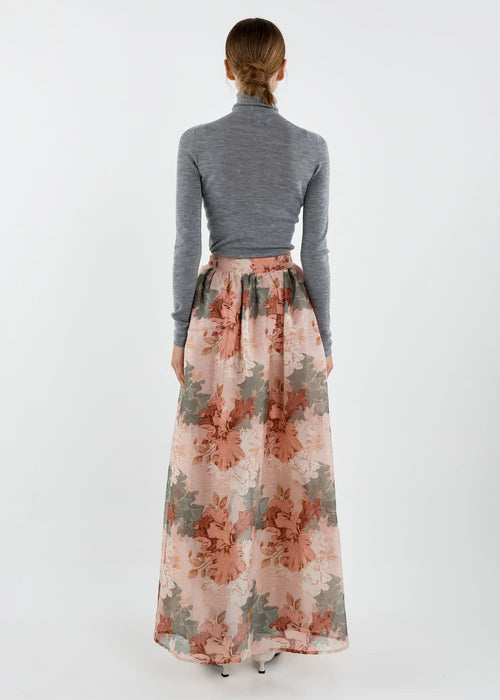 Person wearing a floral skirt and grey top on a white background