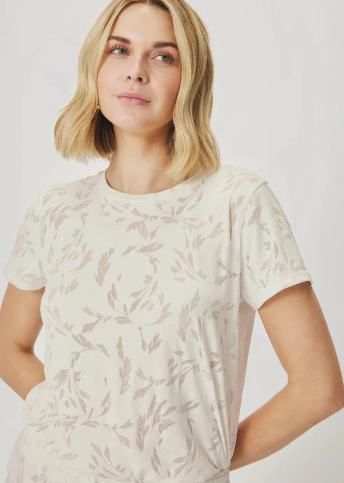 Woman wearing a white t-shirt with a subtle pattern on a plain background