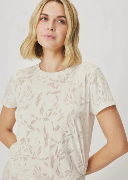 Woman wearing a white t-shirt with a subtle pattern on a plain background