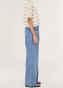 Person wearing a striped shirt and blue jeans on a white background