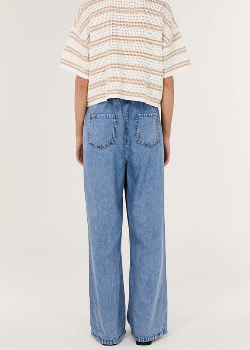 Person wearing a striped shirt and blue jeans on a white background