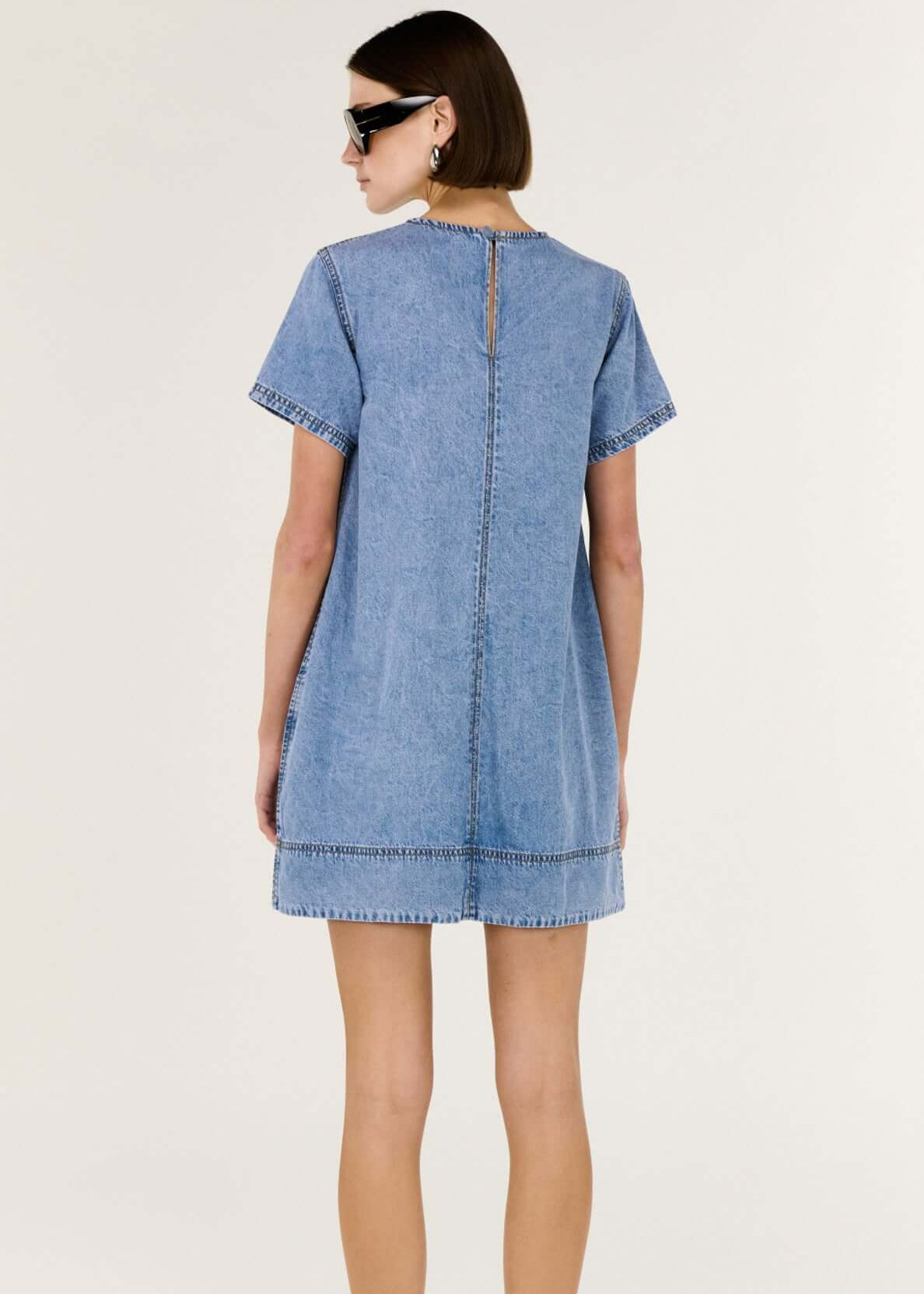 Woman wearing a blue denim dress on a white background