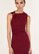 Woman wearing a burgundy dress with a knot detail on a beige background