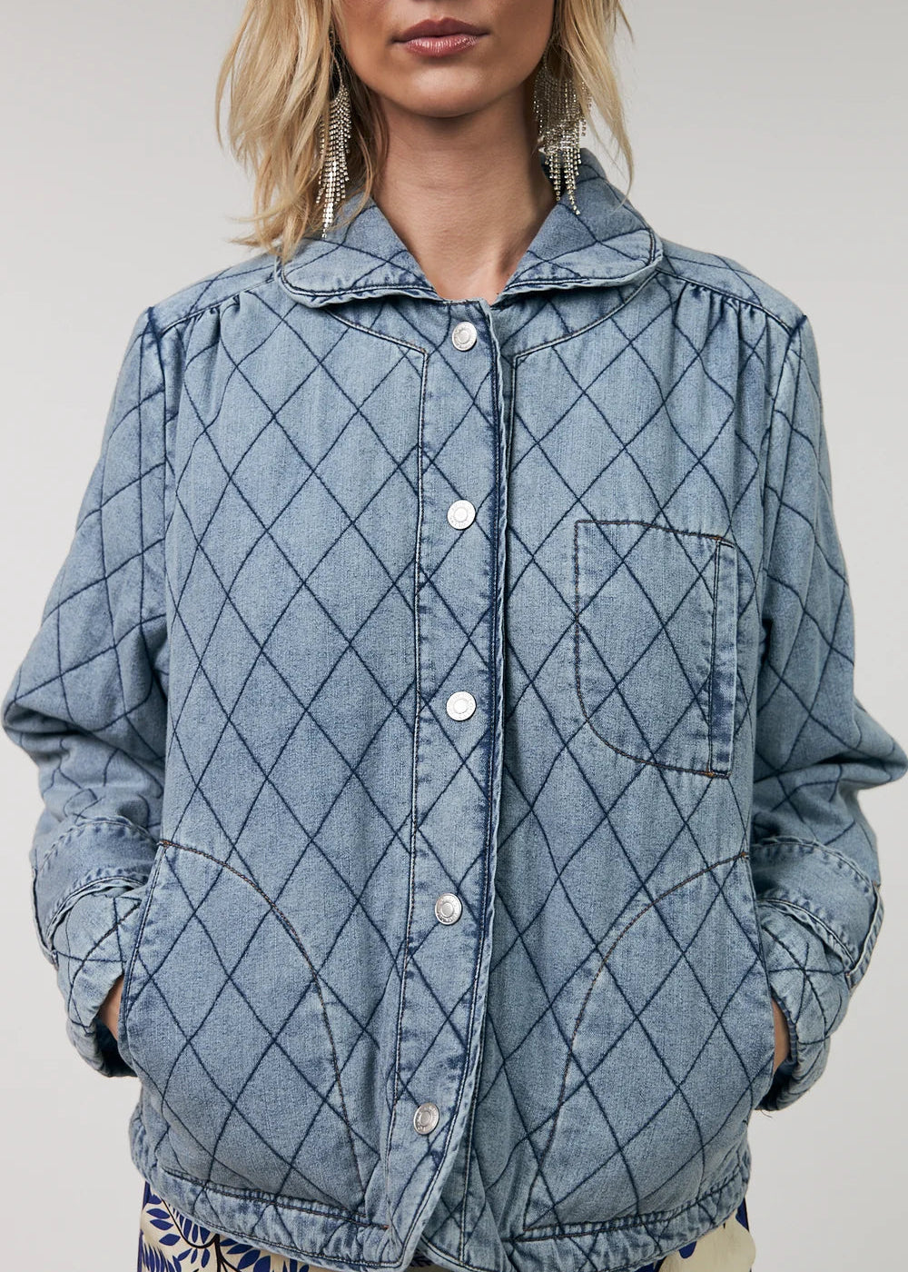 Person wearing a blue quilted jacket with a white background