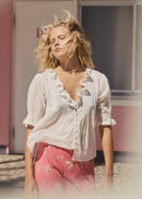 Woman wearing a white blouse and pink floral skirt standing in front of a pink building.