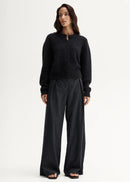 Woman wearing a black cardigan and pants on a white background