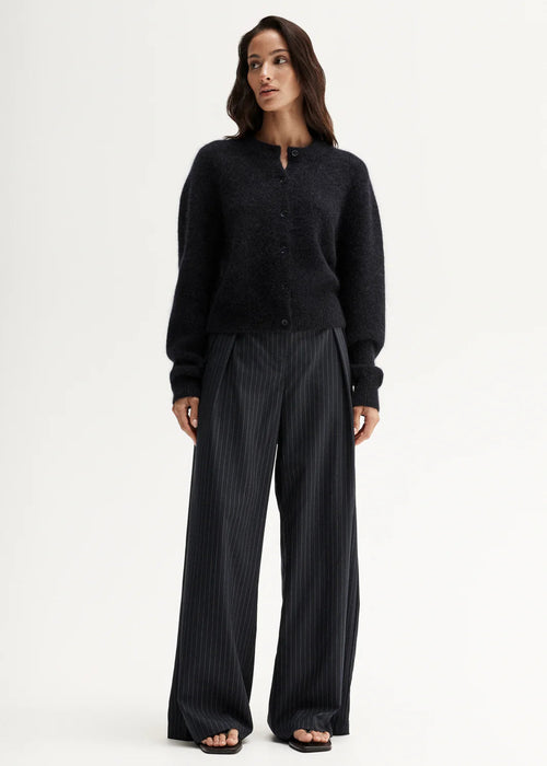 Woman wearing a black cardigan and pants on a white background