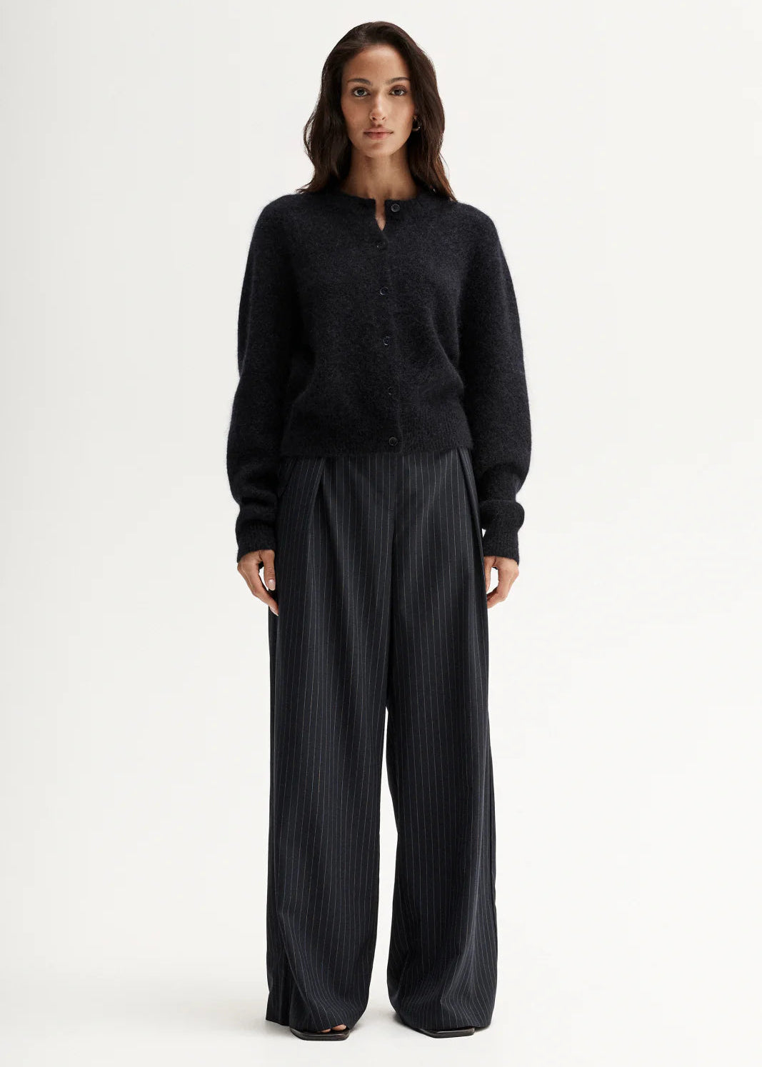 Woman wearing a black cardigan and pants on a white background