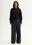 Woman wearing a black cardigan and pants on a white background