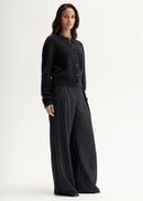 Woman wearing a black cardigan and pants on a white background