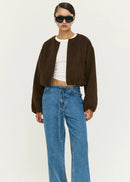 Women wearing a brown jacket, white shirt, blue jeans, and black shoes on a white background