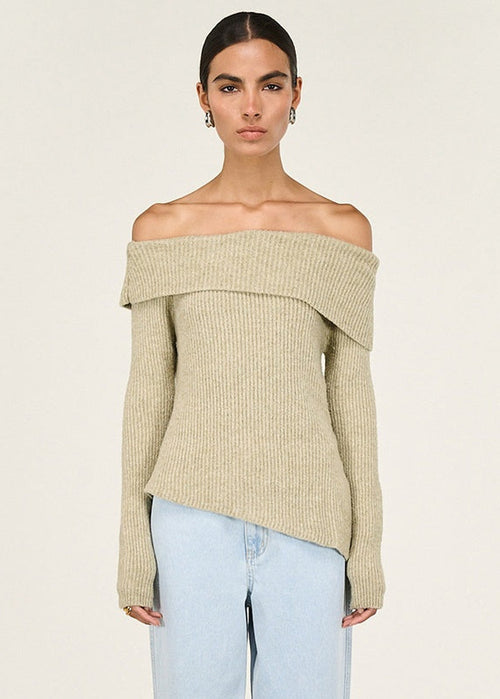Woman wearing a beige off-shoulder sweater against a white background