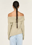 Woman wearing a beige off-shoulder sweater against a white background