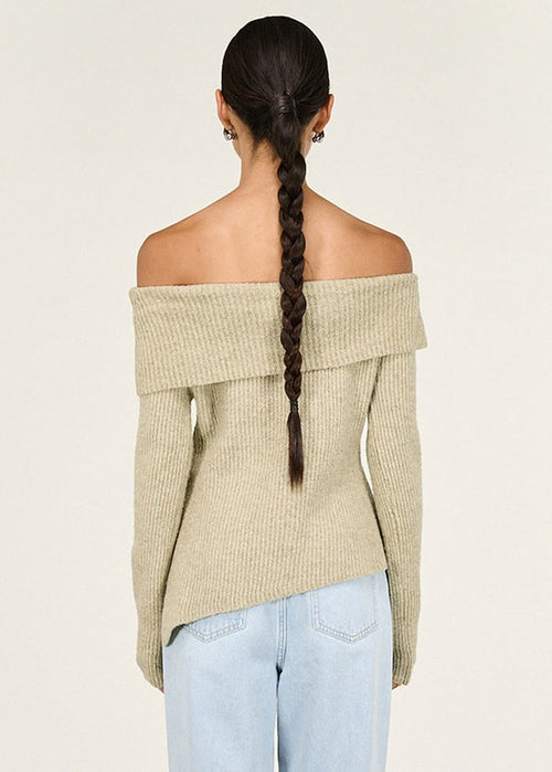 Woman wearing a beige off-shoulder sweater against a white background