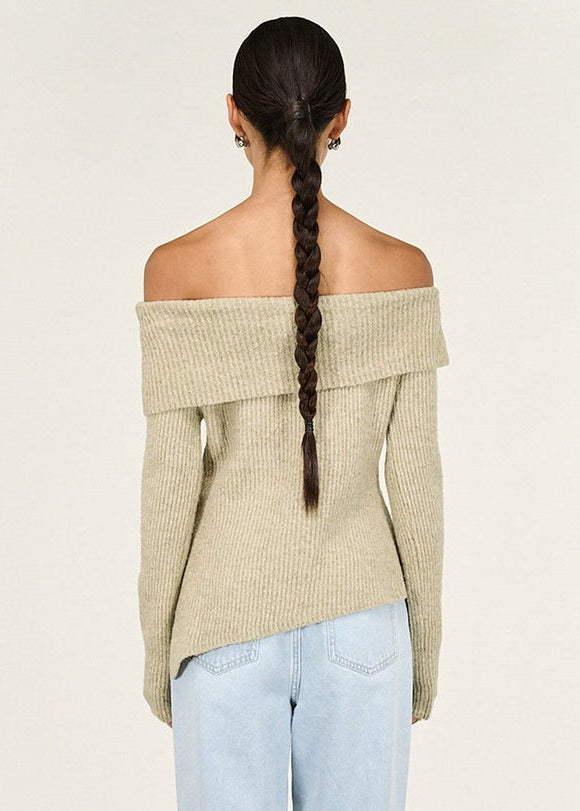 Woman wearing a beige off-shoulder sweater against a white background