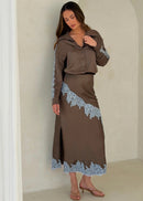 Woman wearing a brown outfit with lace details in a neutral setting