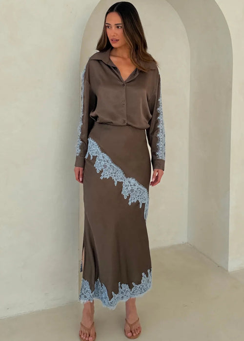 Woman wearing a brown outfit with lace details in a neutral setting